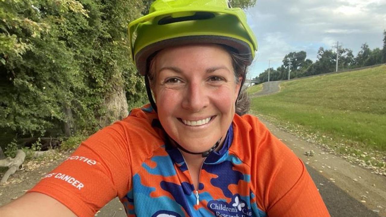 Christine taking a selfie, smiling, as she rides her bike.