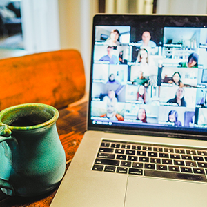 cup of coffee sitting next to a laptop screen in the middle of a conference call