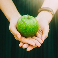 "woman holding a green apple in her hands"