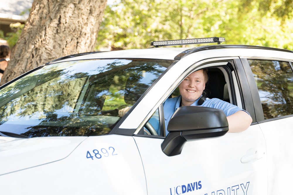UC Davis staff behind wheel of white car branded UC Davis.