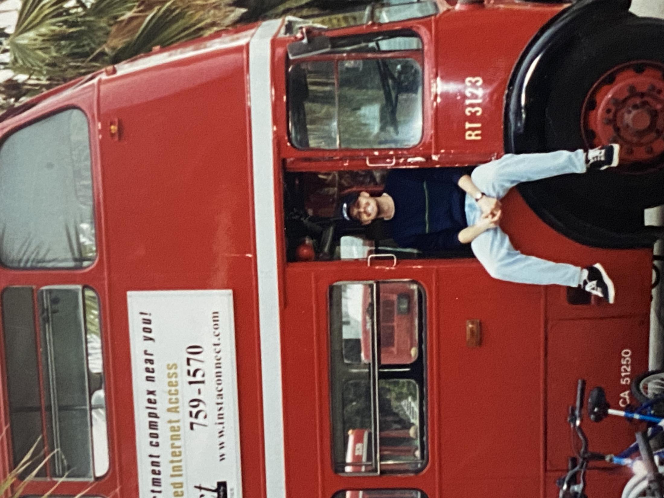 student sitting on stairs of a red bus