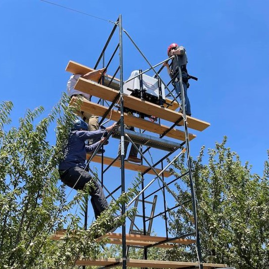 Researchers at the USDA installing a Doppler wind lidar in an almond orchard.