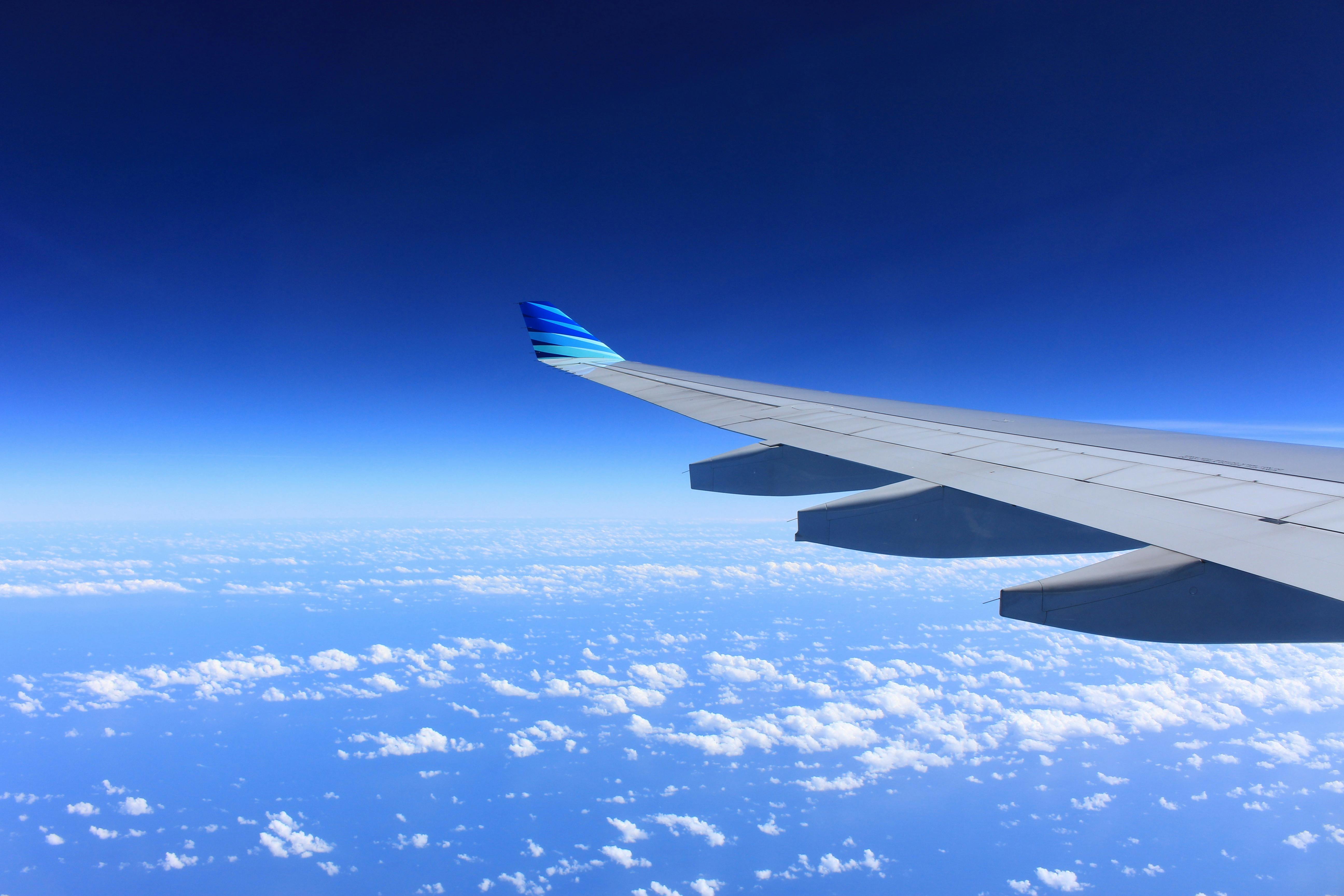 An airplane wing over a blue sky.