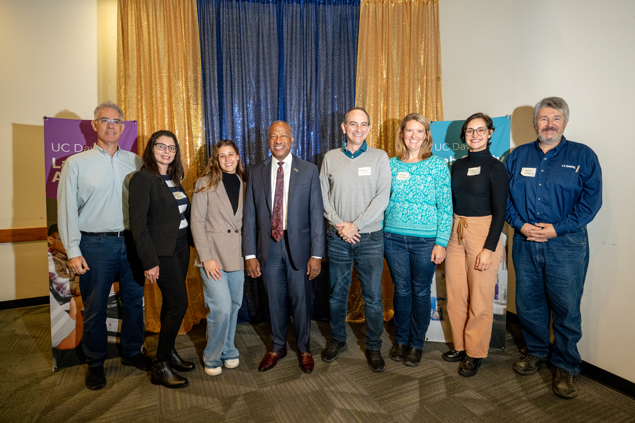 Group photo of ten adults with nametags, smiling before blue and gold curtains