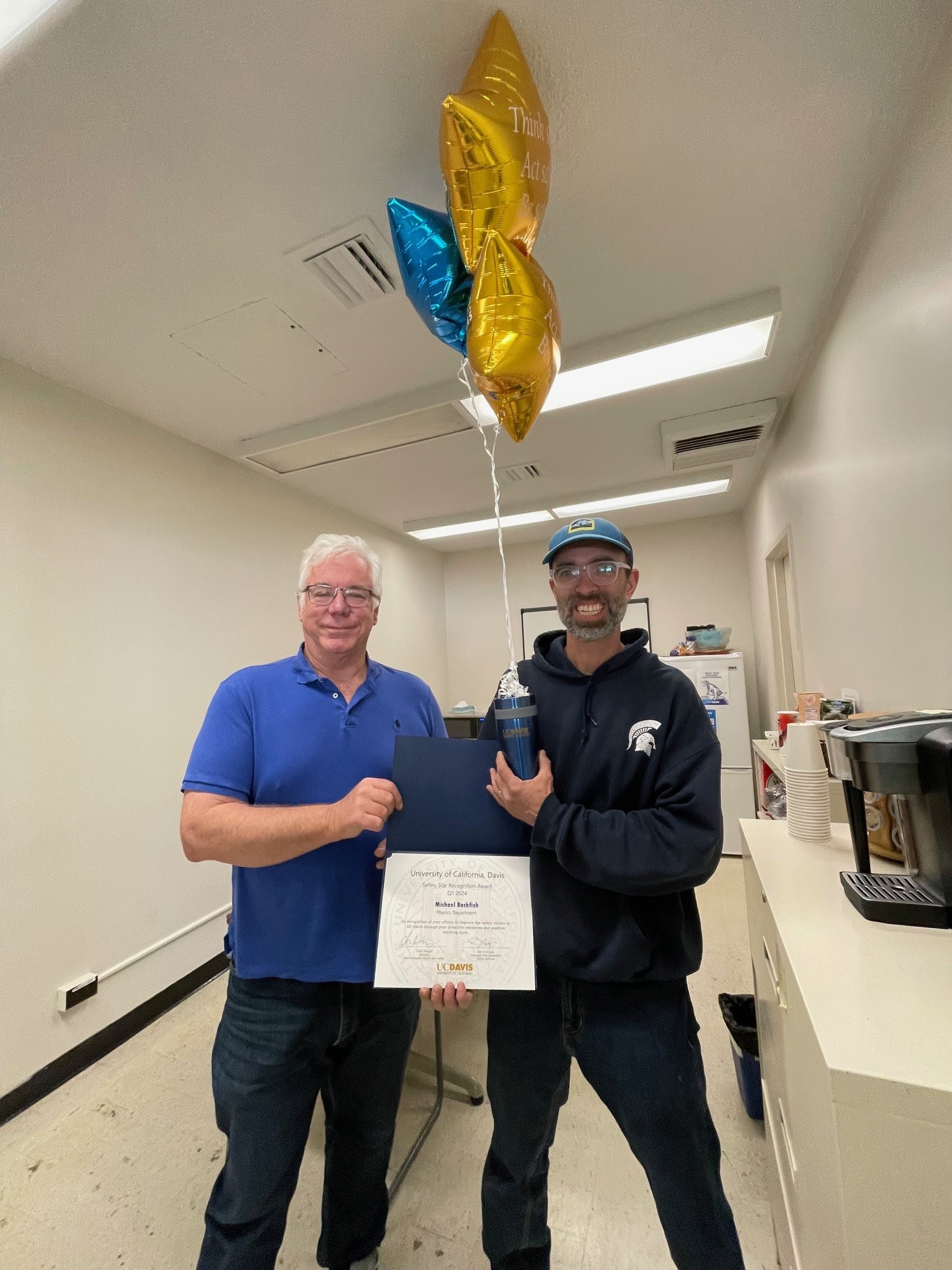 Michael Backfish is presented with the Safety Star award and some star-shaped blue and gold balloons.