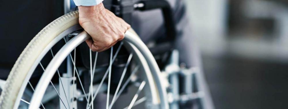 Photo of person seated in wheelchair with hand on right wheel and pushing