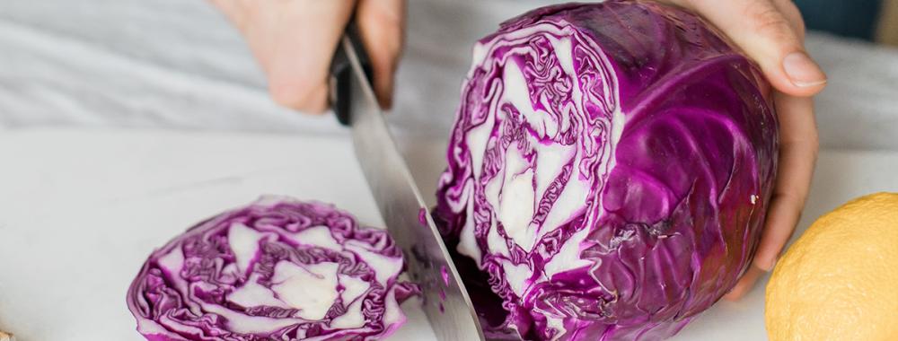 woman chopping up a purple cabbage