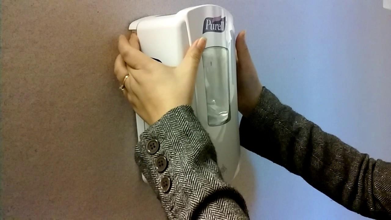 person installing hand sanitizer dispenser on wall