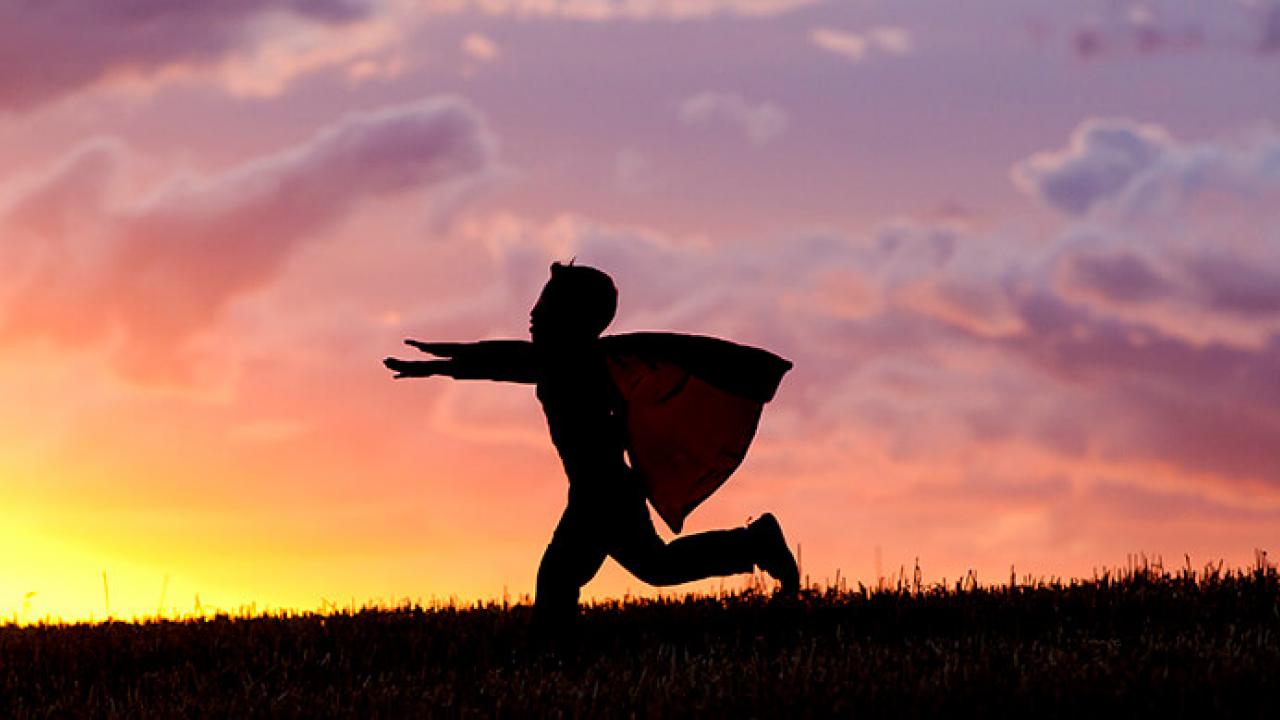 Silhouette of child wearing a superhero cape running