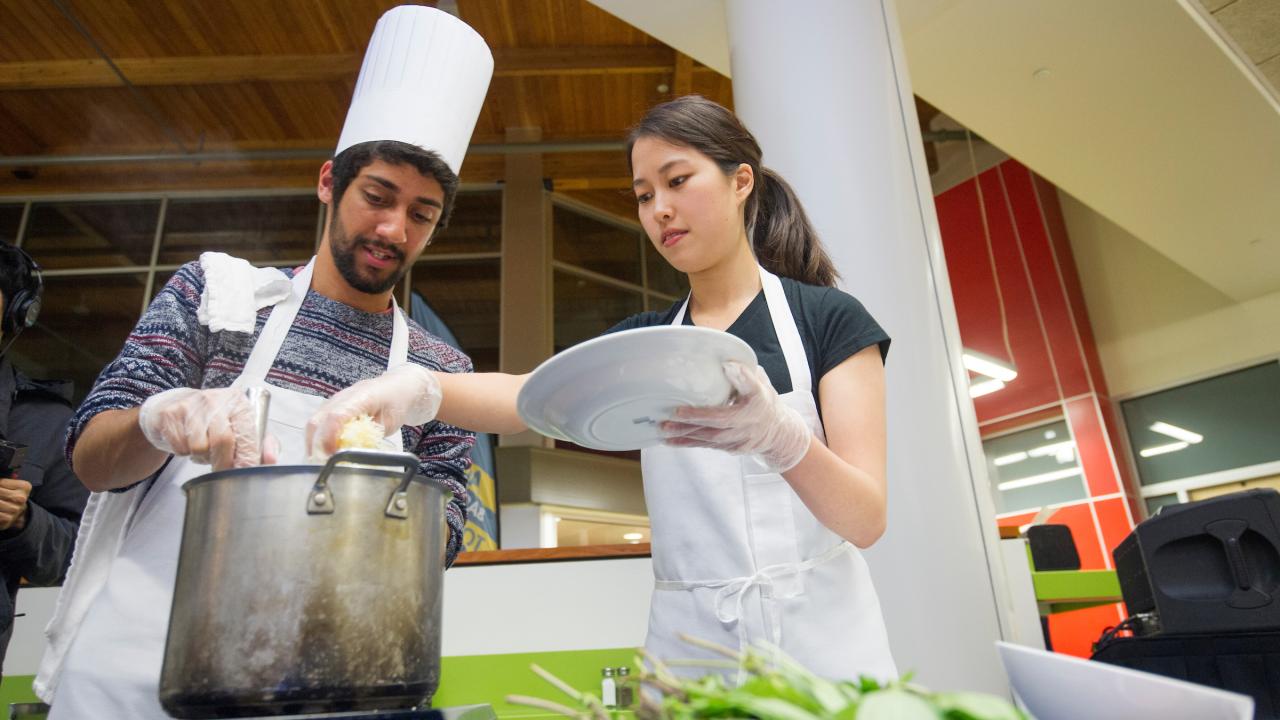 two students cooking in the Segundo Dining Commons for a cooking competition