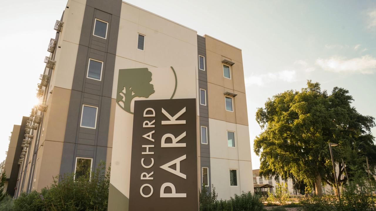 image of the new Orchard Park sign with a housing building in the background