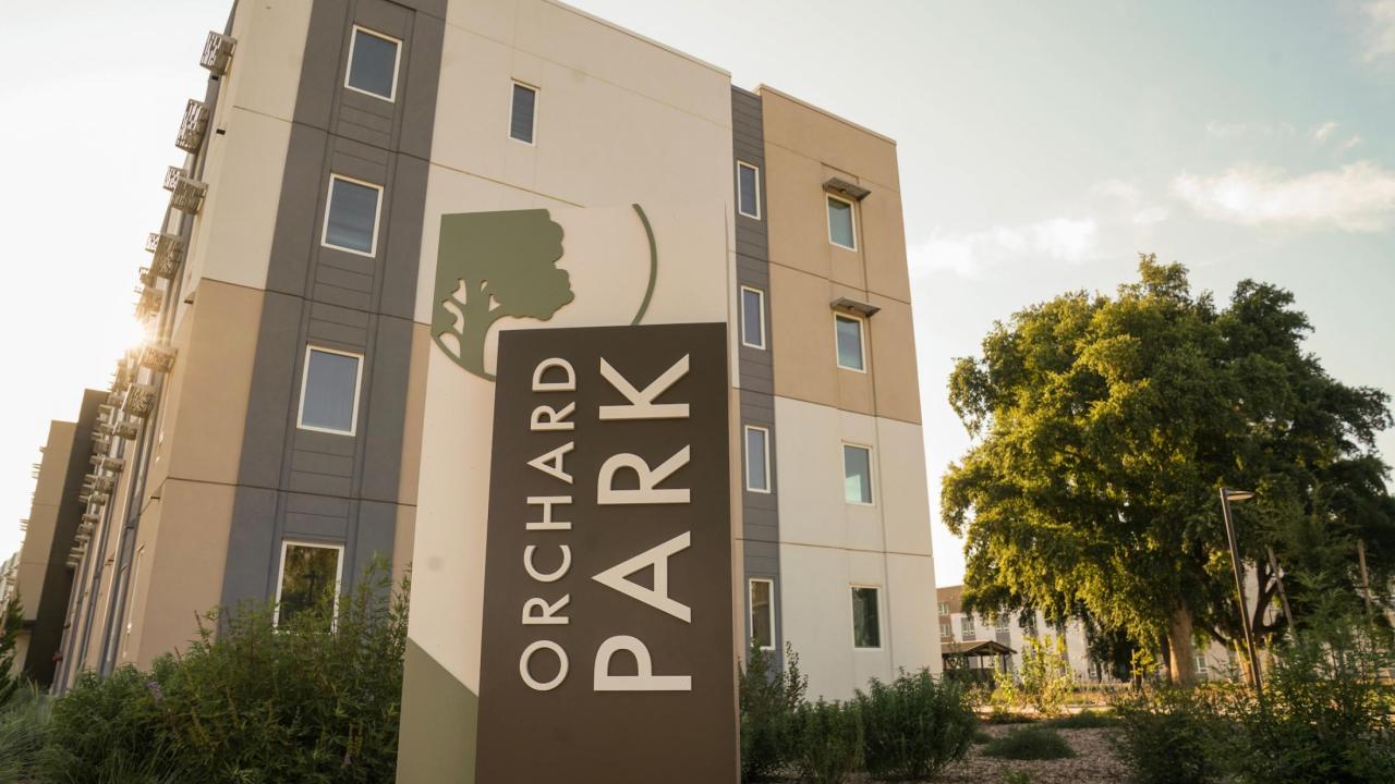 image of the new Orchard Park sign with a housing building in the background