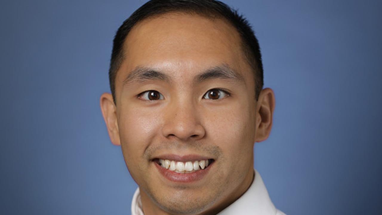 A man wearing a white shirt smiling to the camera.