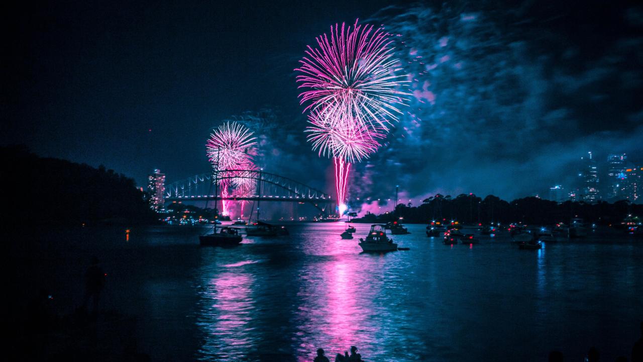 blue and purple fireworks above the Sydney bridge and harbor in the evening