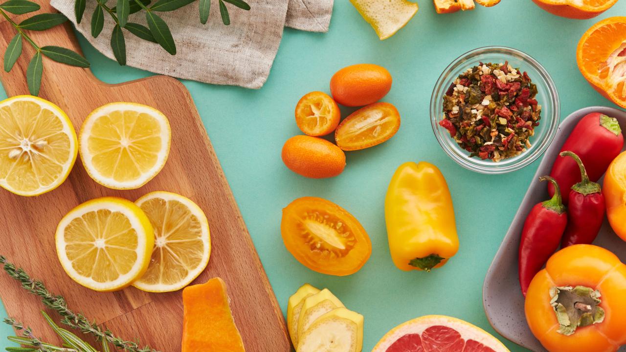 Bright, nutritious fruits are arranged colorfully on a cutting board and blue surface.