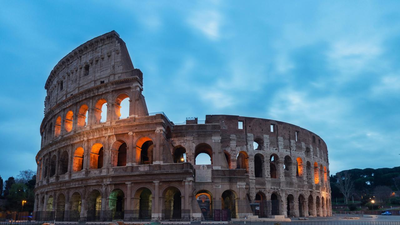 Image of the Coliseum in Rome with a cloudy blue sky in the background