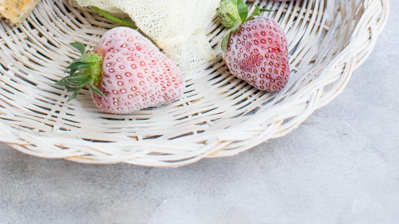 jar of strawberry jam and frozen strawberries on a white plate