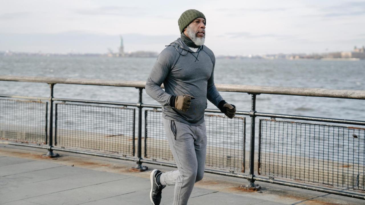 Black man running in NYC, Statue of Liberty and ocean in the background.