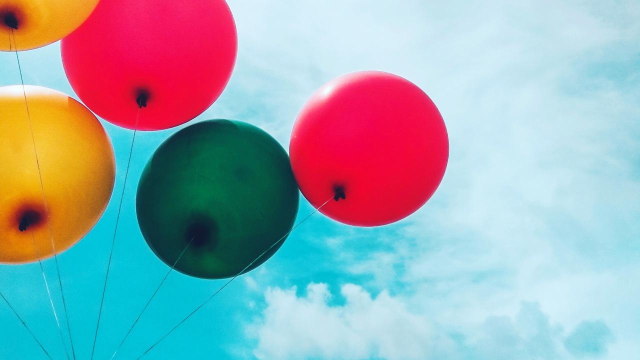 five colorful balloons against a blue sky