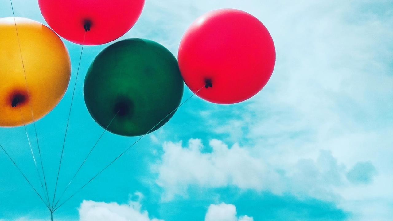 five colorful balloons against a blue sky