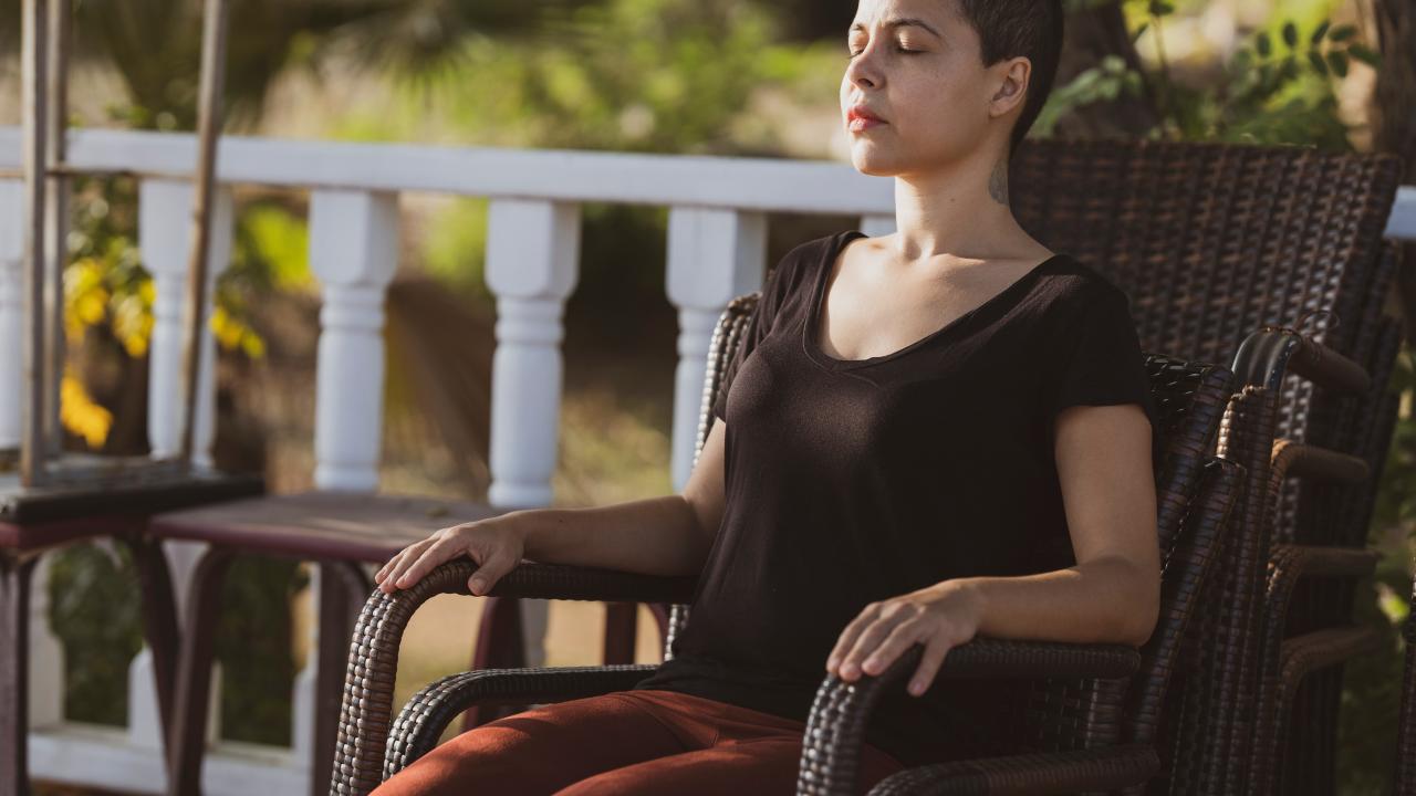 woman sitting on a brown armchair, eyes closed