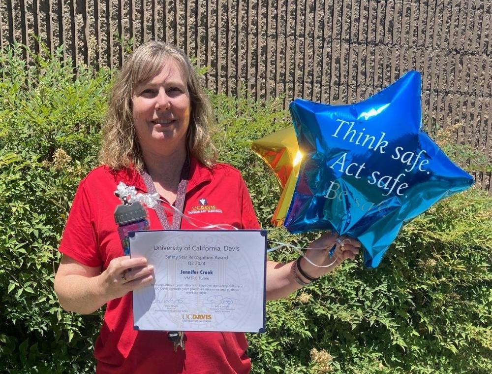 Photo of Jennifer Crook holding a Safety Star award certificate and a blue balloon that reads Think Safe. Act Safe.