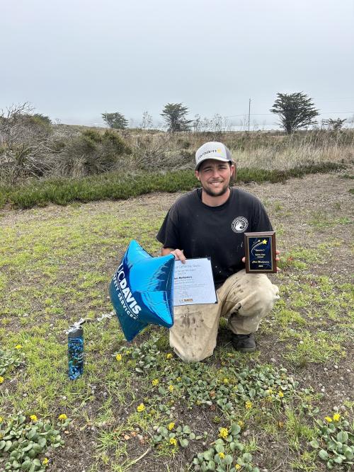 Chris Montgomery holding a star balloon and certificate for his recent Safety Star Award, while posing at Bodega Marine Lab