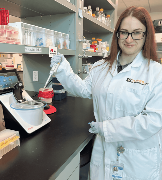 Lab manager Diana Polhac uses a pipette in the lab and smiles at the camera.