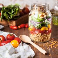 a light salad with tomatoes greens and grains in a glass jar