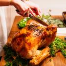 woman carving a cooked turkey at a dinner table
