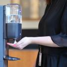 person with hand placed under sanitizer dispenser.