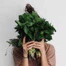 woman holding a bunch of green leafy vegetables in front of her face