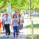 Group of people smiling and walking along a path with green in the background