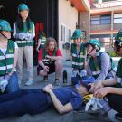 CERT team huddles around a person laying on the floor to practice disaster preparedness
