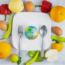 Small globe on a plate surrounded by fruits and veggies