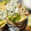 image of a burrito cut in half with rice, avocado and chicken wrapped in a tortilla which is wrapped in foil